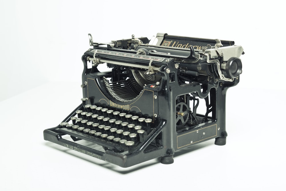 máquina de escribir negra y gris sobre mesa blanca