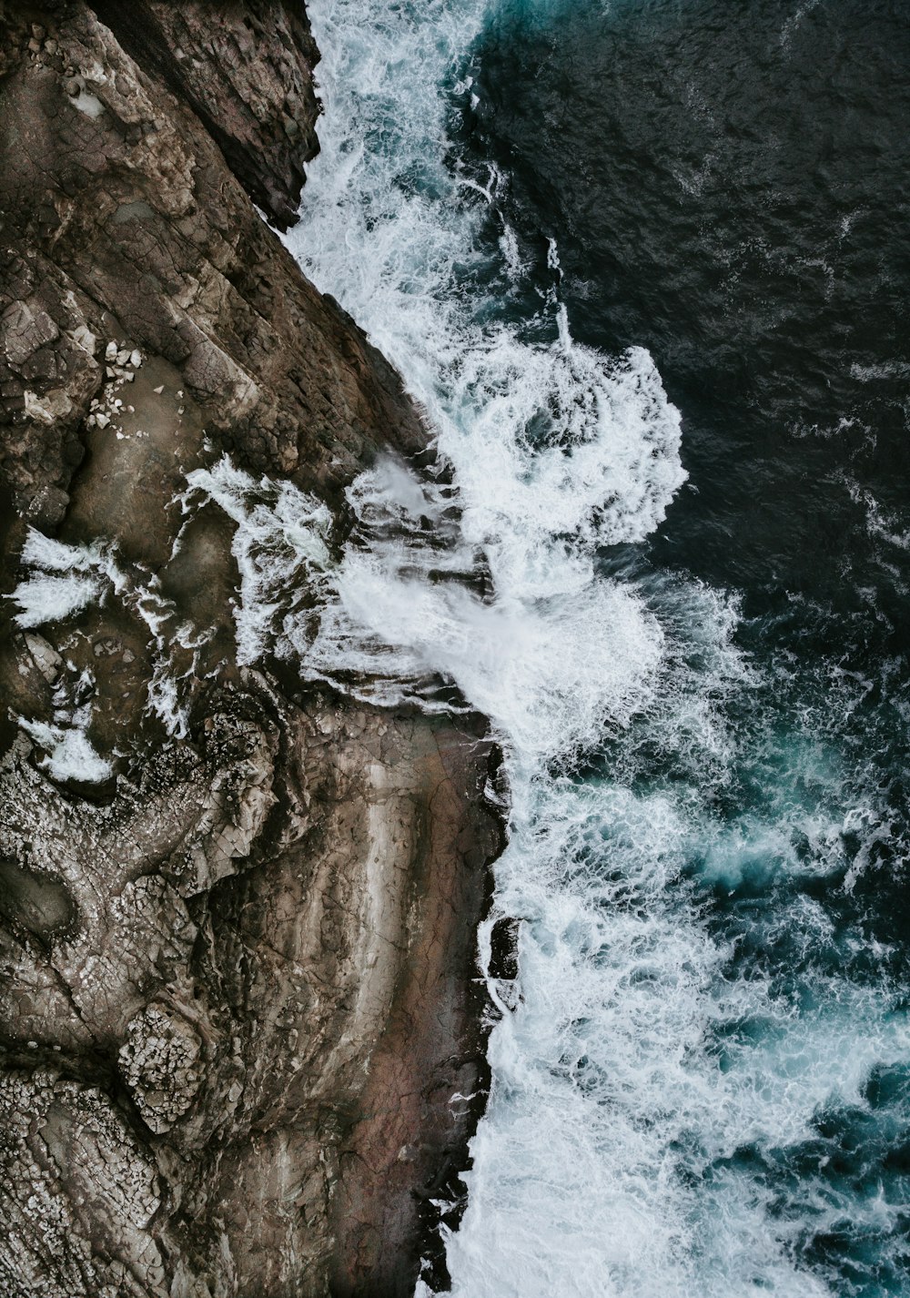 A vista de pájaro, olas de agua chocando contra las rocas