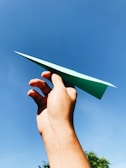Close-up of hands folding a paper airplane with bright patterned paper.