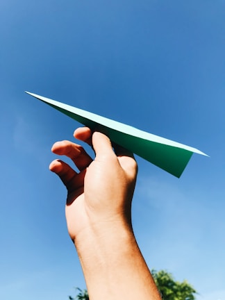 Close-up of hands folding a paper airplane with bright patterned paper.
