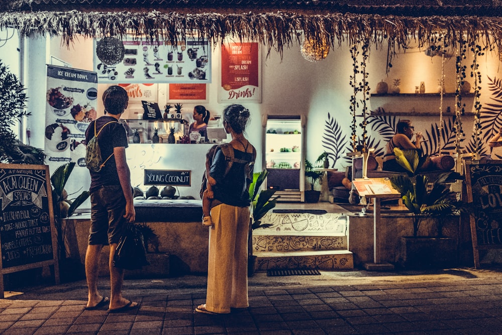 mujer cargando a un bebé de pie frente a la tienda