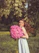 A smiling woman holding a small bouquet of wildflowers, radiating warmth and confidence in a sunlit park.
