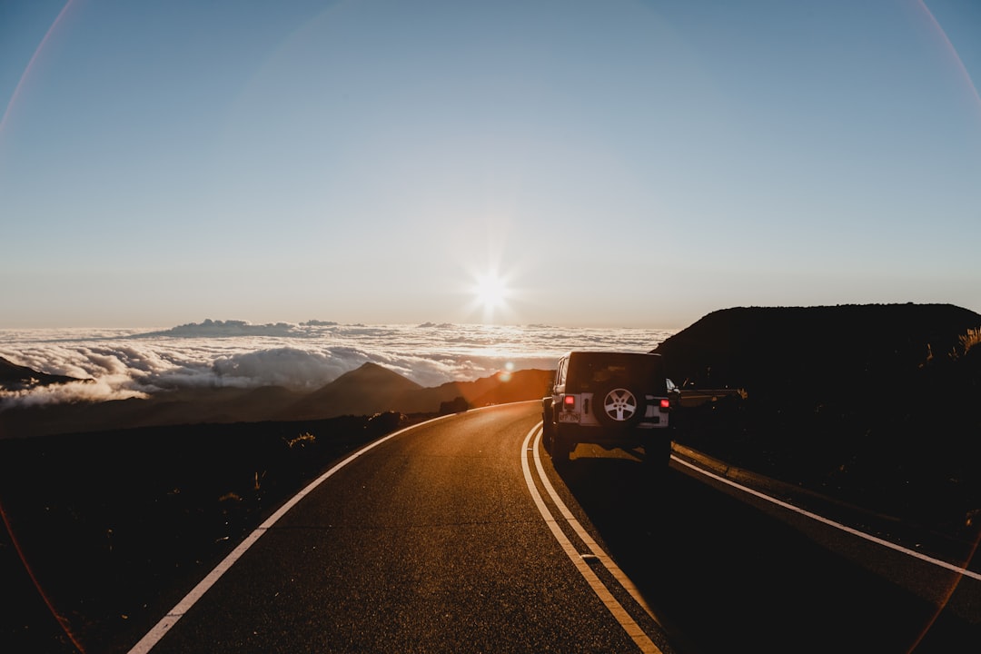 SUV passing road, We got up at 3am to drive up to the top of Haleakalā National Park and see the sunrise. We’d heard everyone talk about how incredible it was and something we had to whilst on the island but never did we think it would leave us as speechless as it did. The slow sunrise and clouds like waves, rolling over the volcanic landscape, was something that I can’t imagine I’d ever experience again.<p></figure>When the sun had risen, we started walking back down to where we had left our car and I managed to capture this shot. I feel like it perfectly sums up that feel of adventure literally on top of the world.