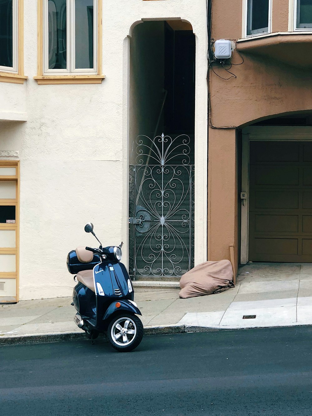 scooter preta estacionada perto de casa de concreto bege