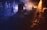 A live music performance with a band on stage, surrounded by a smoky atmosphere. The lighting is dramatic with warm spotlights illuminating the band members, creating a contrast with the dark, shadowy background.