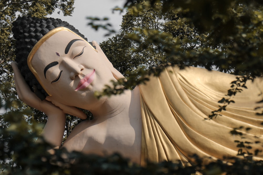 Bouddha en béton brun et beige couché entouré d’arbres pendant la journée
