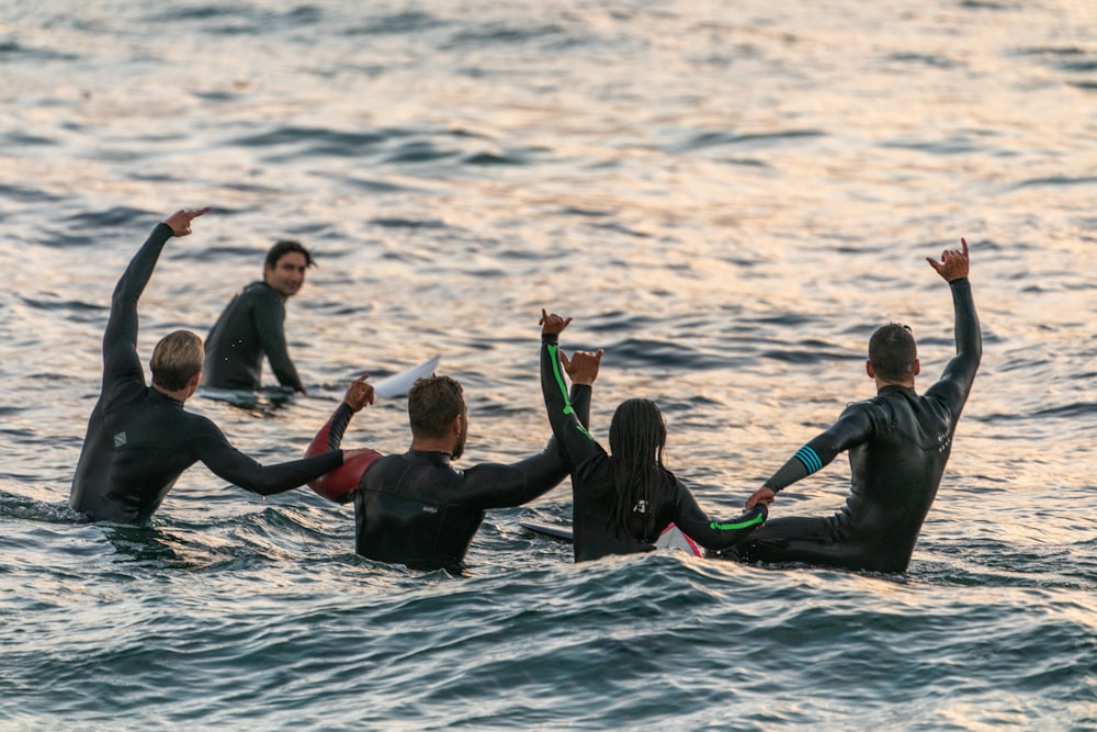 Personas con trajes de neopreno negros en el cuerpo de agua