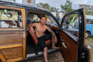 man sitting on brown leather vehicle seat during daytime