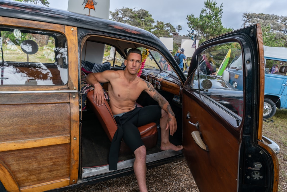 man sitting on brown leather vehicle seat during daytime