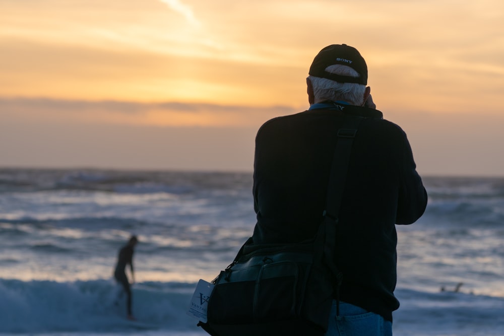 uomo che scatta foto di surfista in spiaggia