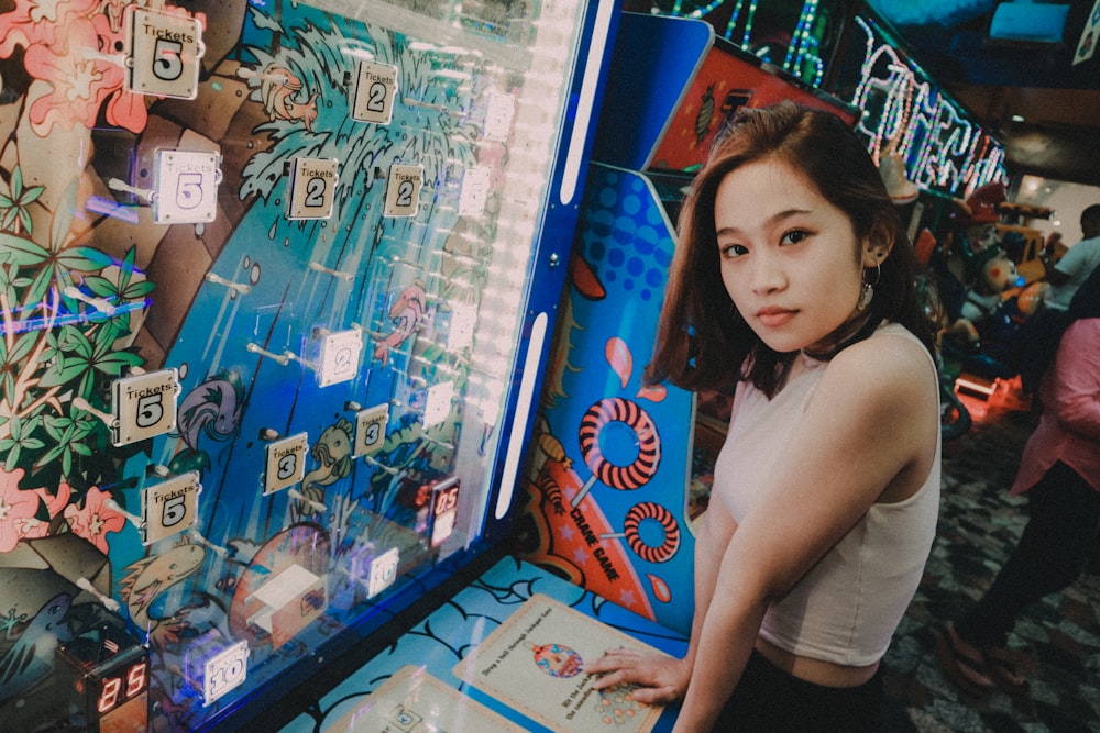 woman wearing white top standing in front on the blue slot machine