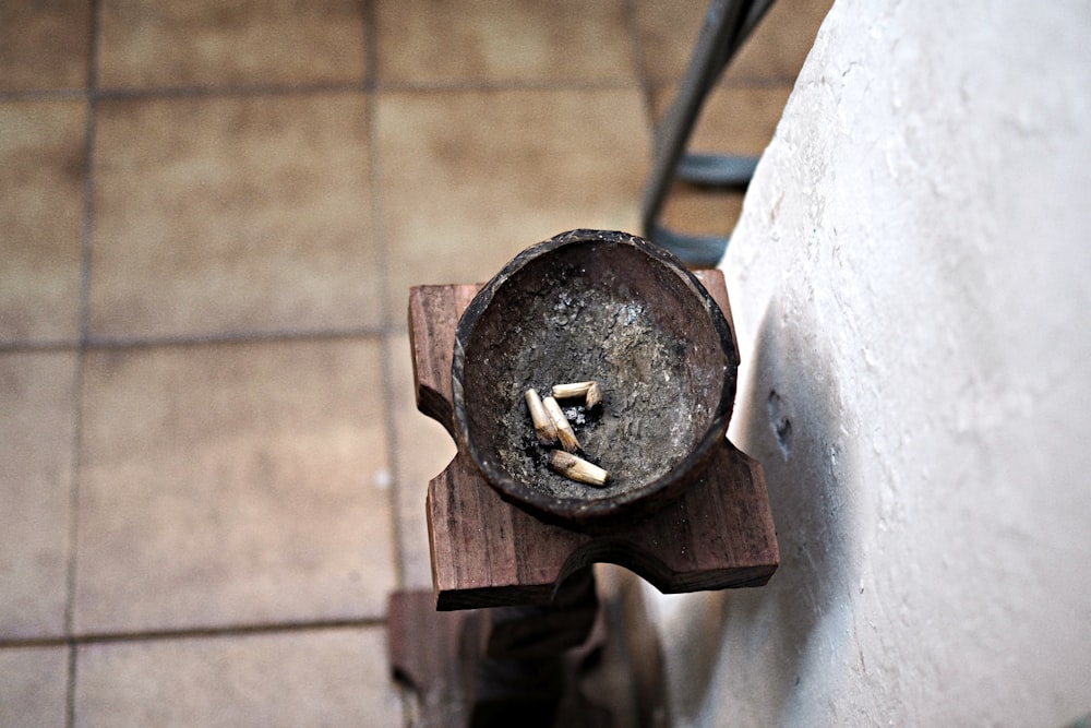 round brown wooden ashtray with white cigarette butts on brown wooden stand