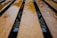 Close-up view of wooden planks with a glossy, wet surface. The planks are arranged in parallel lines, likely forming the seat of a bench, with raindrops scattered across them. The background is blurred, focusing attention on the texture and shine of the wet wood.