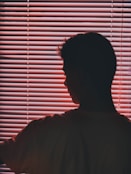 man in white crew-neck t-shirt near pink vinyl blinds