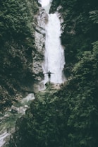 man standing at the cliff in front of the fall