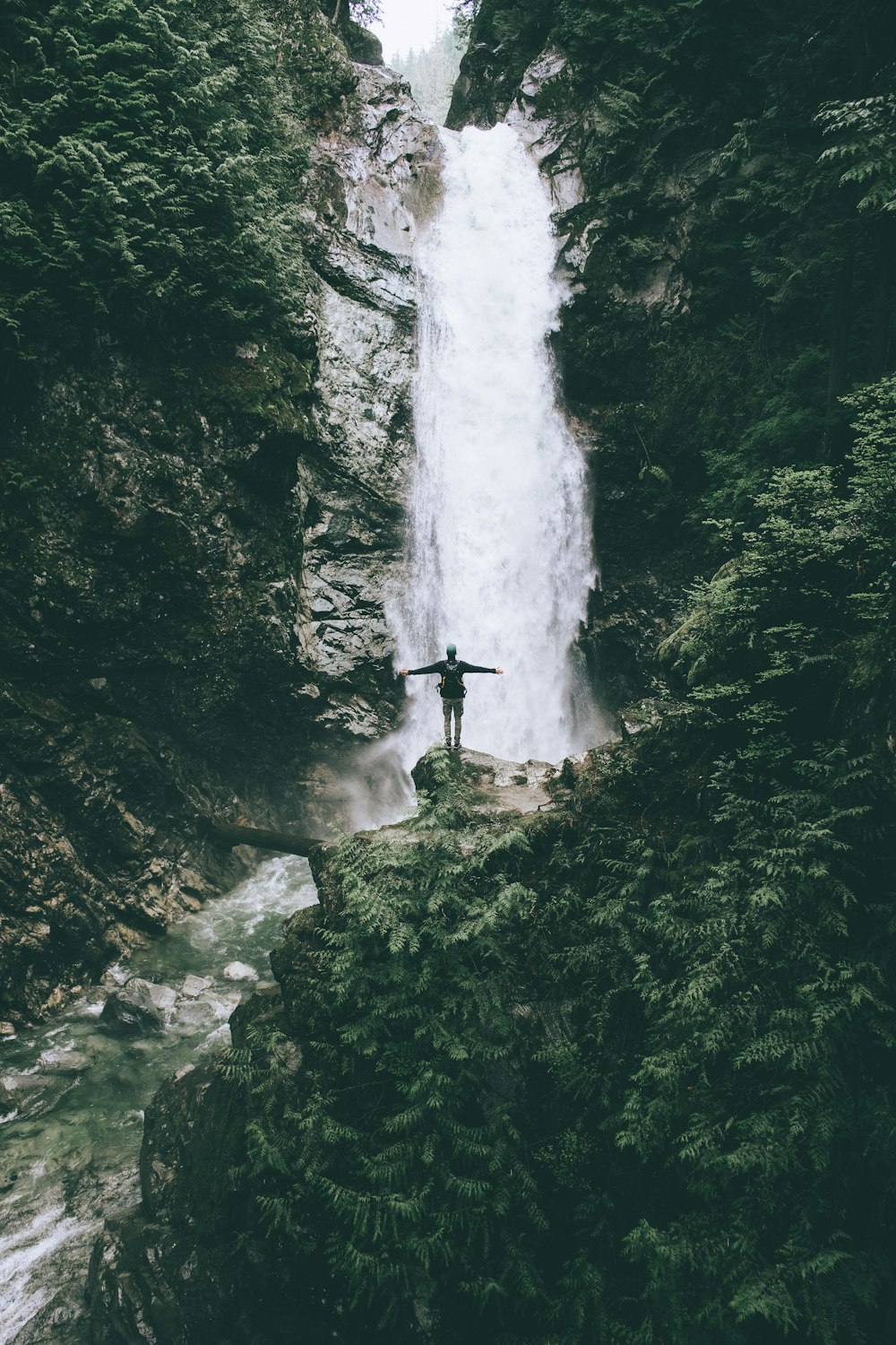 滝の前の崖に立つ男