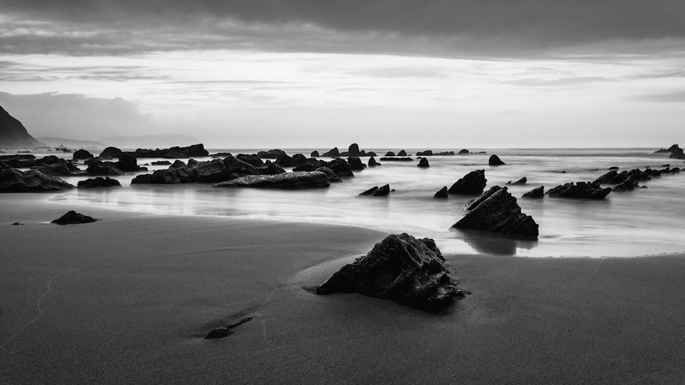 grayscale photo of big rocks surrounded by body of water