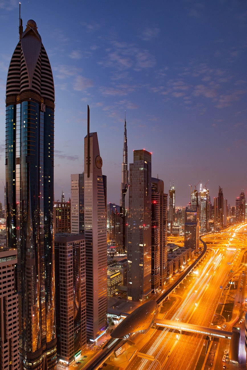 The Dubai skyline at dusk, the city still lit and the day not yet over.