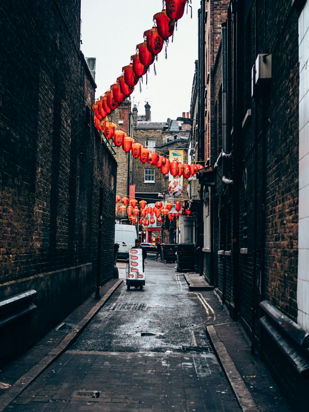 lanterne chinoise rouge accrochée à des bâtiments en béton gris pendant la journée
