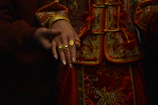 Close-up of a couple's hands intertwined, showcasing intricate gold thread details on their garments.