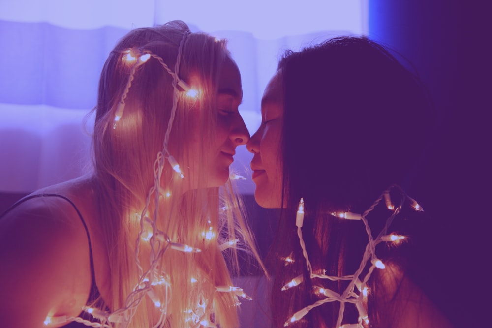 two woman facing each other with string lights