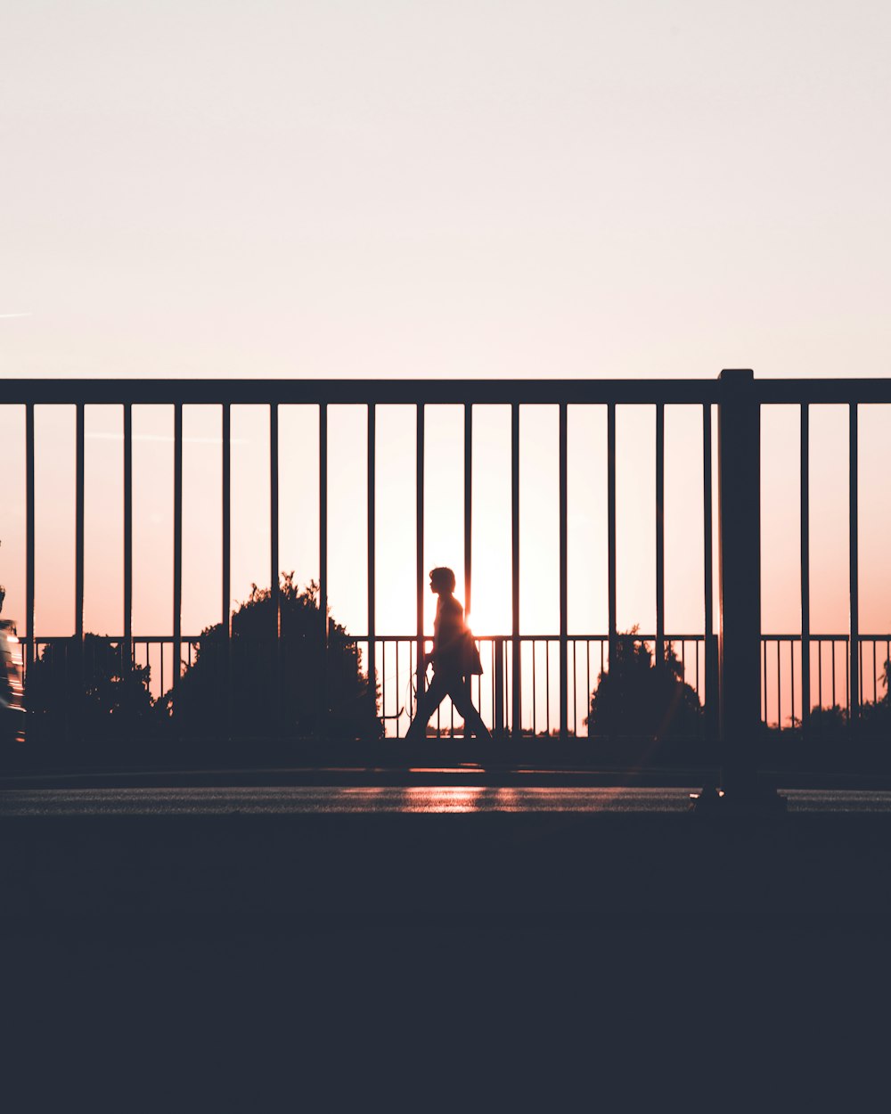 Silhouette einer Person, die während des Sonnenuntergangs am Straßenrand spazieren geht