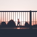 silhouette of person walking on roadside during sunset