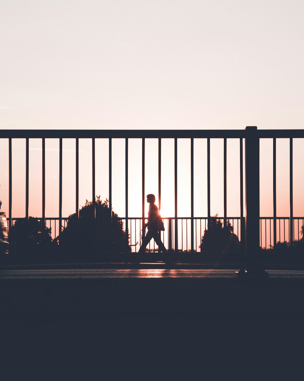 silhouette of person walking on roadside during sunset