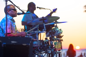 Musicians smiling and playing percussion instruments during a sunset outdoor gig