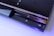 A sleek, black gaming console with a glossy finish is shown. The console features a disc drive, the PlayStation logo, and illuminated icons. The Sony branding is visible on the lower part, and the console is highlighted with a soft blue lighting accentuating its modern design.