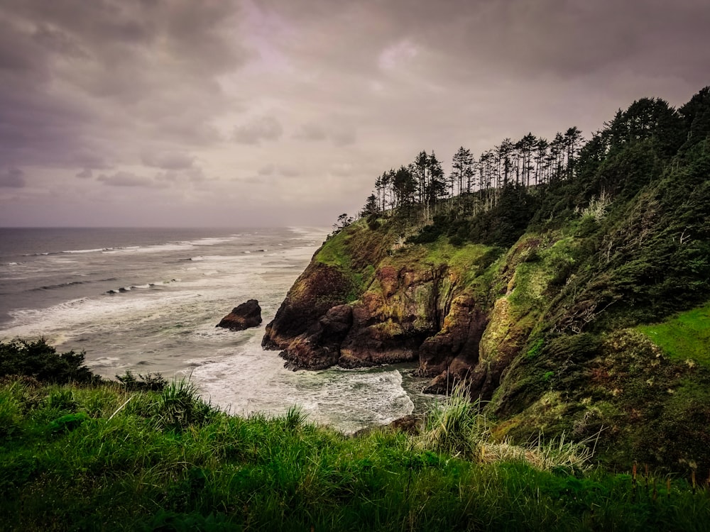 sea waves beside green and brown rocky cliff