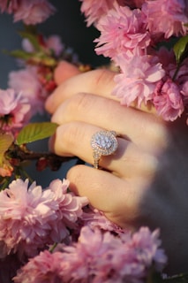 Hands adorned with sparkling lab diamond rings gently holding a blooming flower.