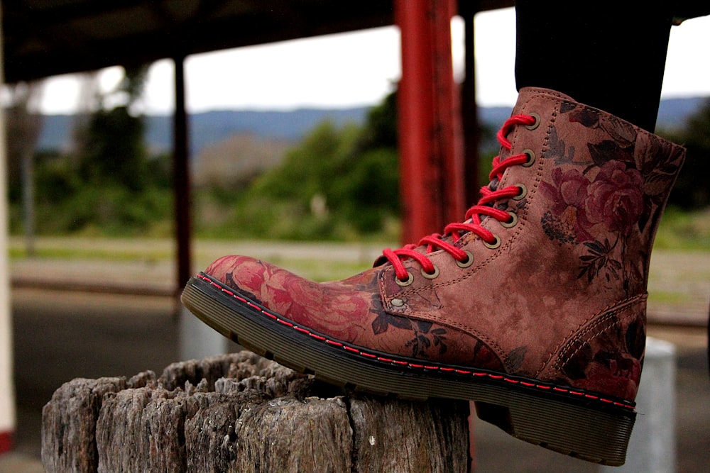 unpaired brown and red floral leather boot on foot