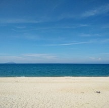 A serene tropical beach with calm waters and clear skies.