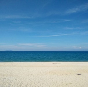A serene beach with clear blue waters and a vibrant sunset.