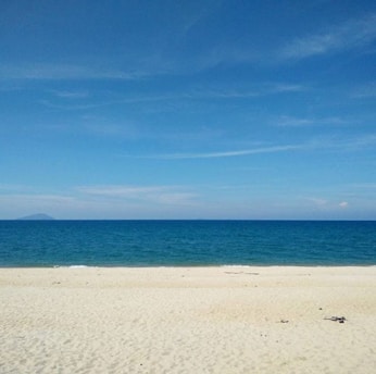 A serene beach with clear blue water and soft white sand under a bright sky.