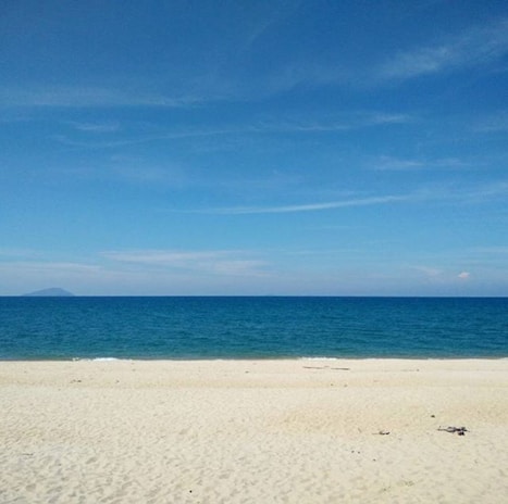 A serene beach with soft white sand and clear blue waters under a bright sky.