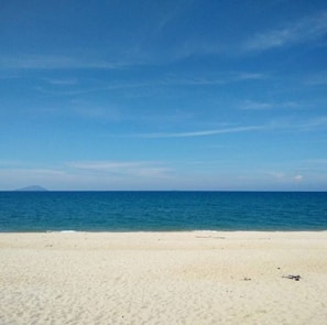 A serene beach view with golden sands and clear blue waters.