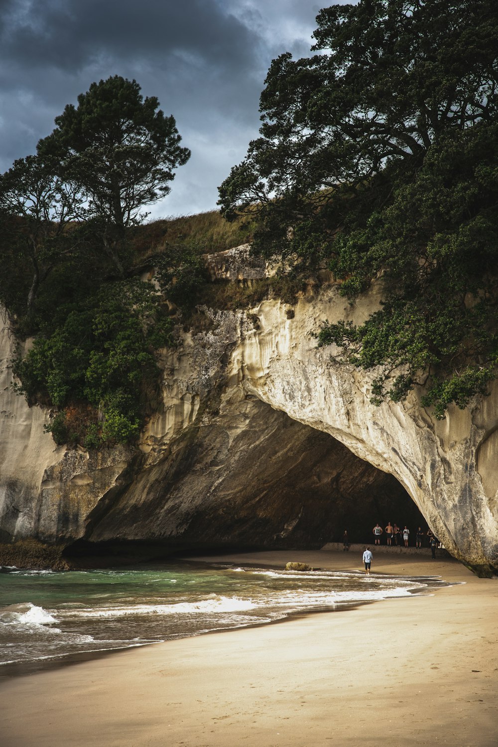 Personas dentro de una cueva cerca de la orilla del mar durante el día