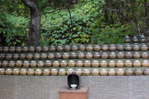 Rows of handmade crafts and pottery arranged neatly on wooden tables with greenery in the background
