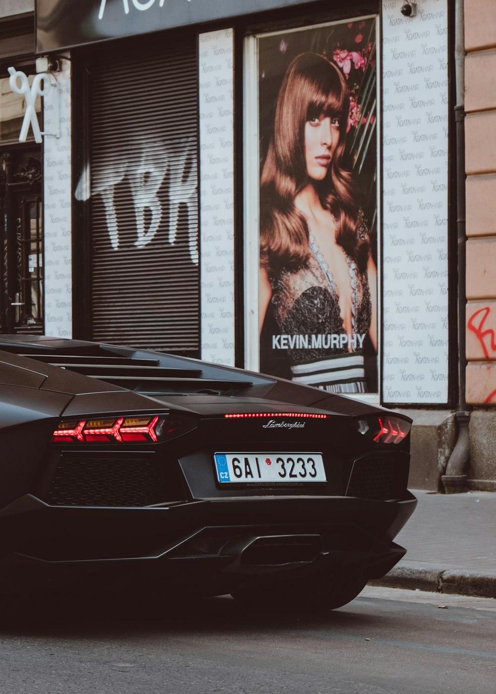 Lamborghini preto ao lado do pôster de Kevin Murphy