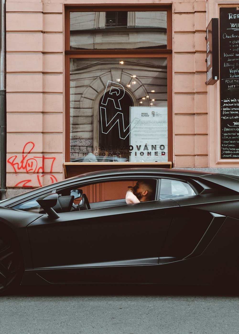 man inside black coupe beside restaurant