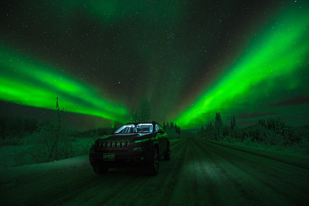 auto nera su strada sotto l'aurora boreale