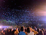 A crowd of people in deep reflection under a sky filled with shimmering particles and light beams.