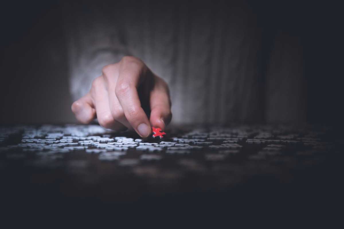 A hand placing the final piece into a jigsaw puzzle, symbolizing the transition from tech to management roles