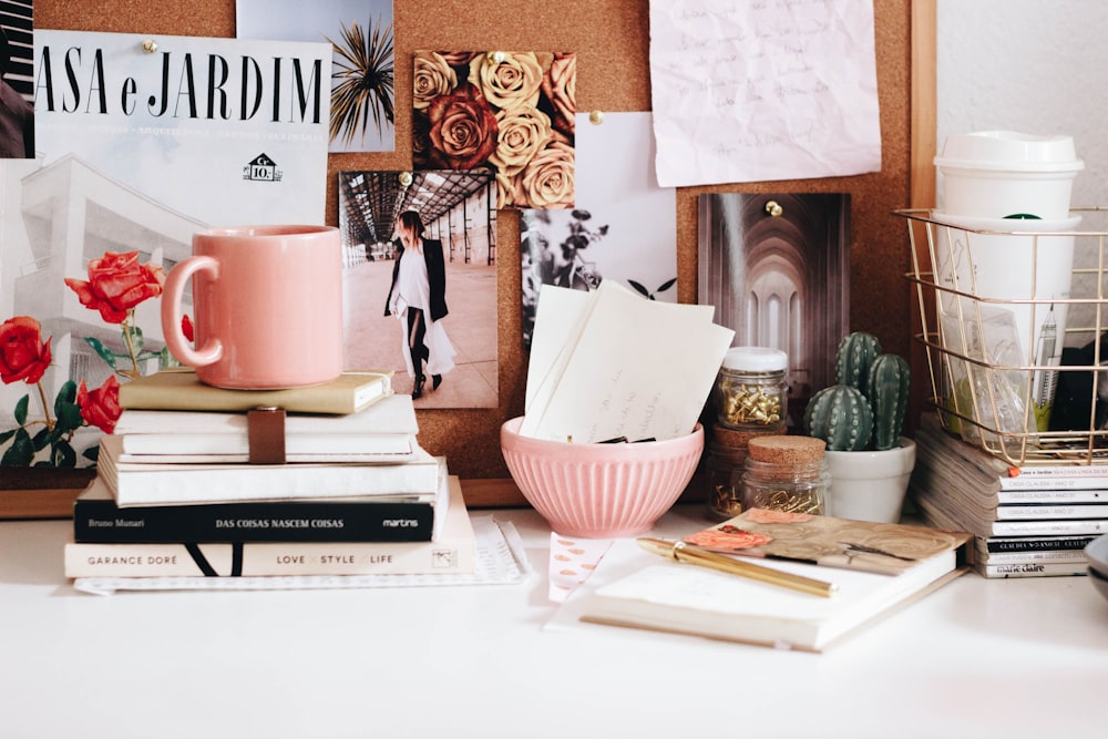 Caneca rosa em livros empilhados