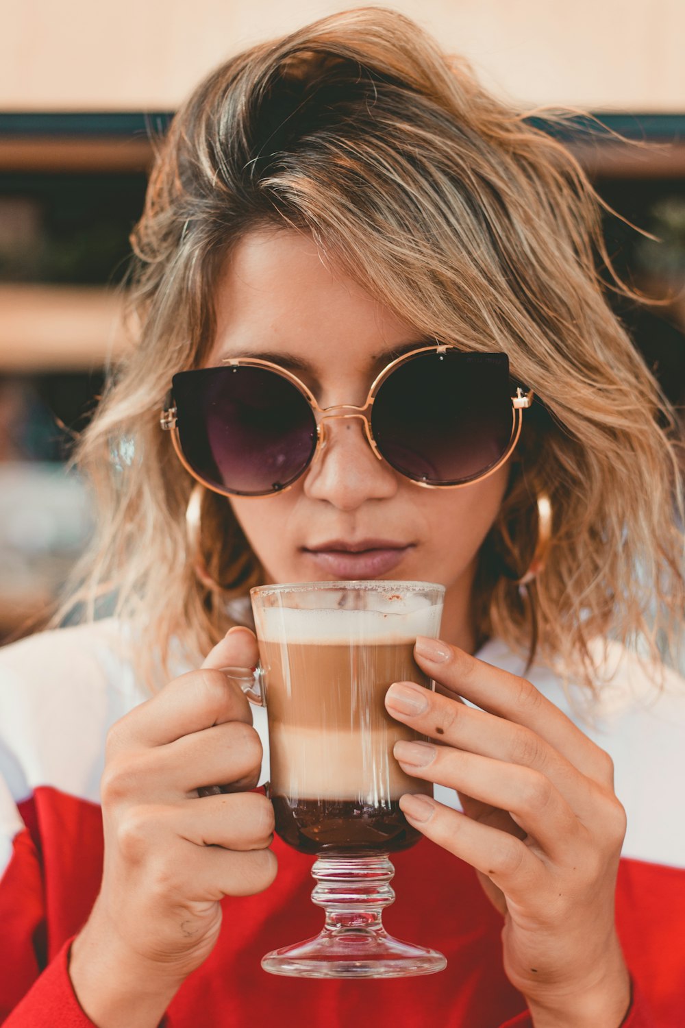 woman holding clear footed mug about to drink a coffee