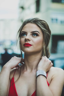 Date night style with a sleek black dress and bold red lipstick, posed against a softly lit restaurant backdrop