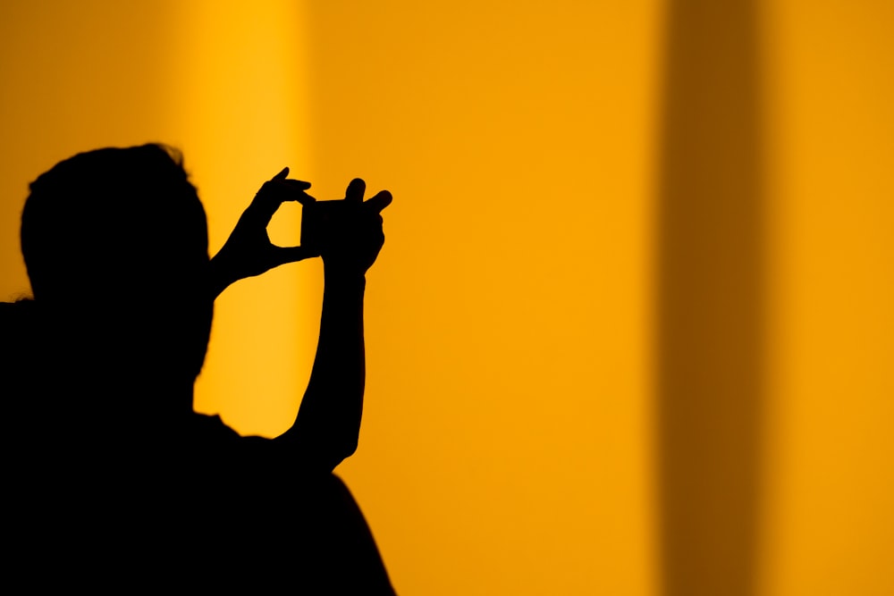 silhouette di uomo che scatta foto usando la macchina fotografica