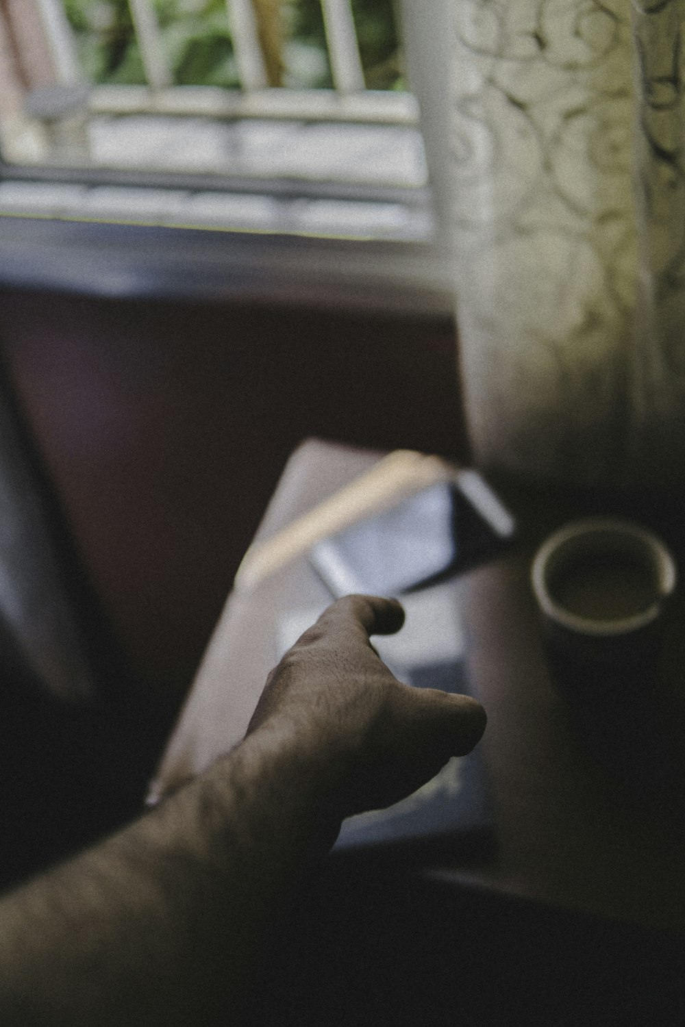 selective focus photo of person reaching out to book on table